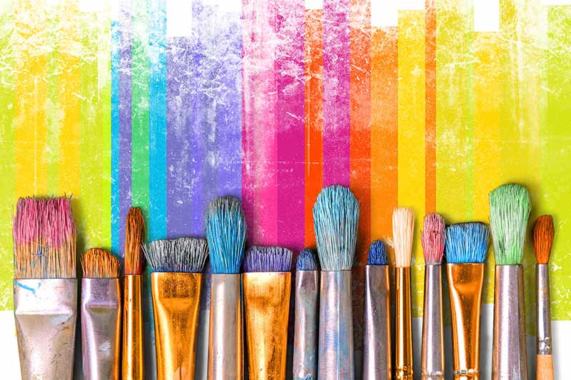 Colorful streaks of paint with a row of paint brushes