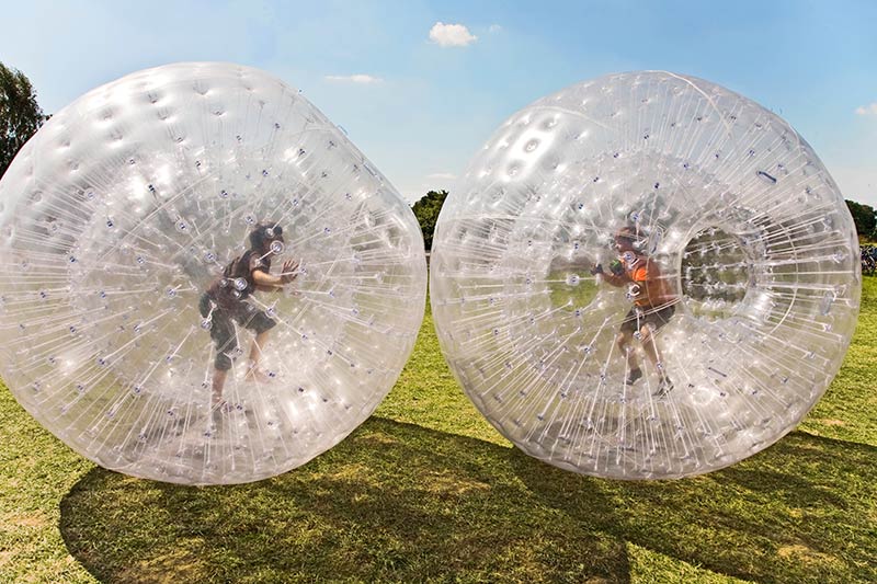 Two people zorbing in a giant inflatable ball